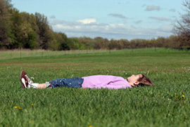 Mergaitė užsimerkusi guli pievoje